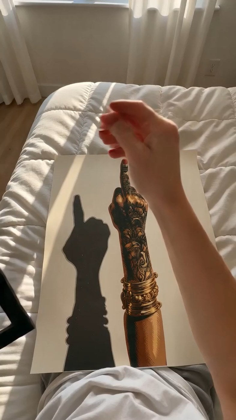 Plakaten Løftet finger med henna ligger udrullet på en seng i morgenlys